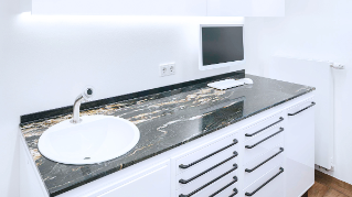 Dark stone counter top with sink and drawers inside a treatment room of the Zähne im Zentrum practice in Münster.