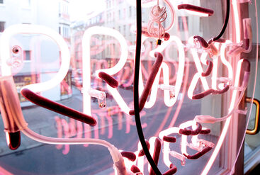 An eye-catcher in the window - lettering in neon pink of the Praxis Mitte, in Berlin.