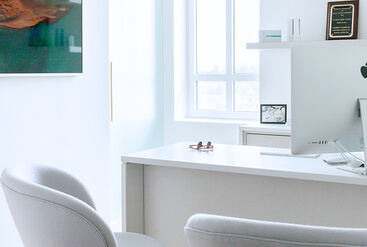 Consultation room in a dental practice with chairs in front of a desk.