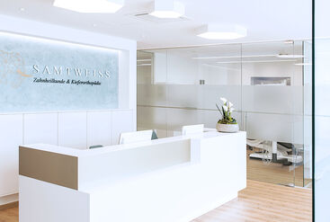 Reception desk in dentist's office in soft white. Glass walls in the background