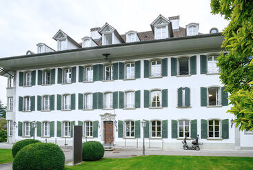 A historic building in green surroundings.
