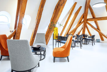 Waiting room of a dental practice. The visible wooden beam look is part of the interior design in soft earth tones.