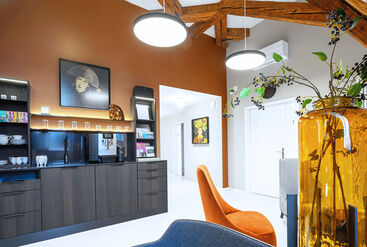 Waiting room of a dental practice with stylish interior design in earth tones, wooden beam look and a coffee bar.